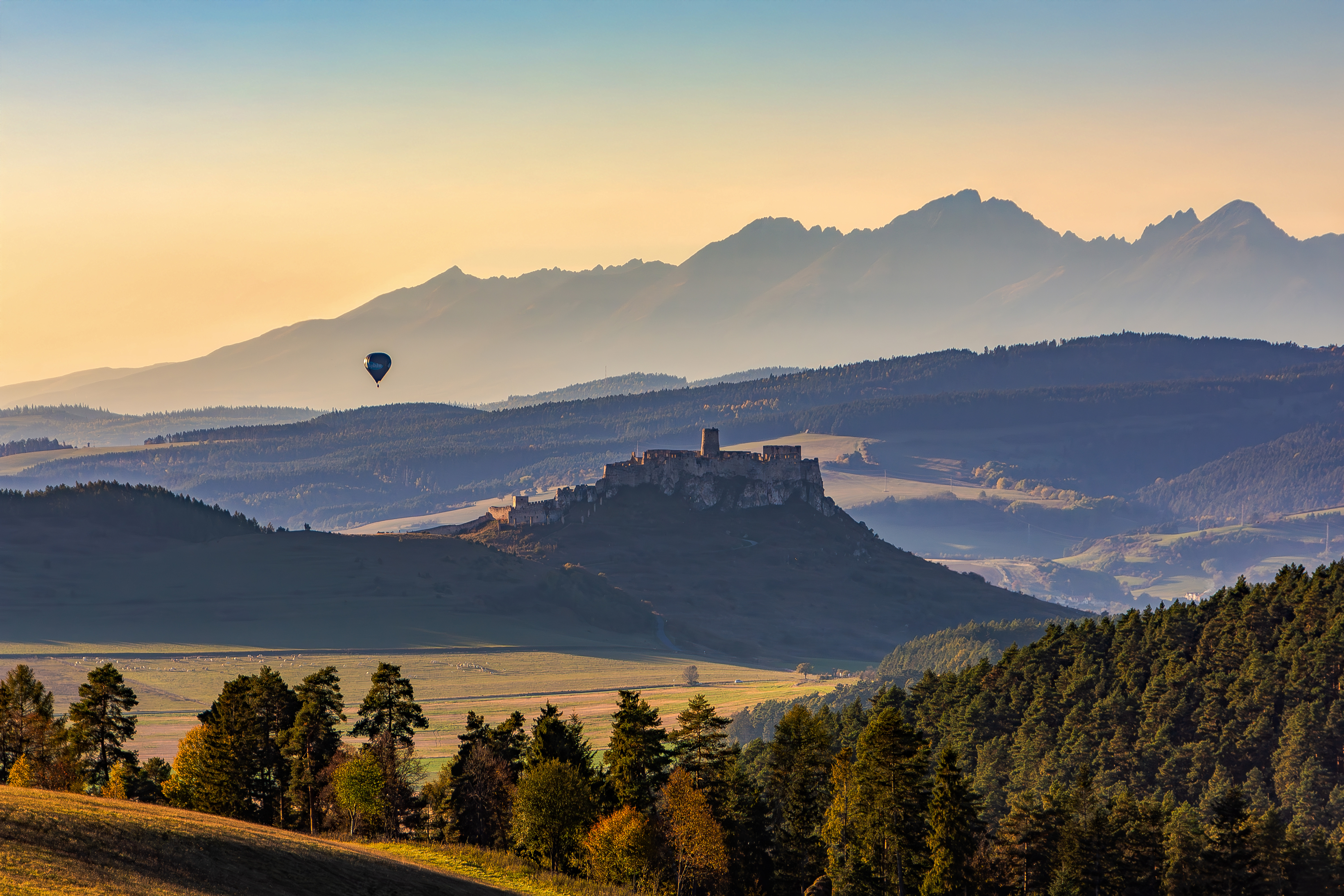 Letecký pohľad na Spišský hrad s balónom a panorámou Tatier pri západe slnka