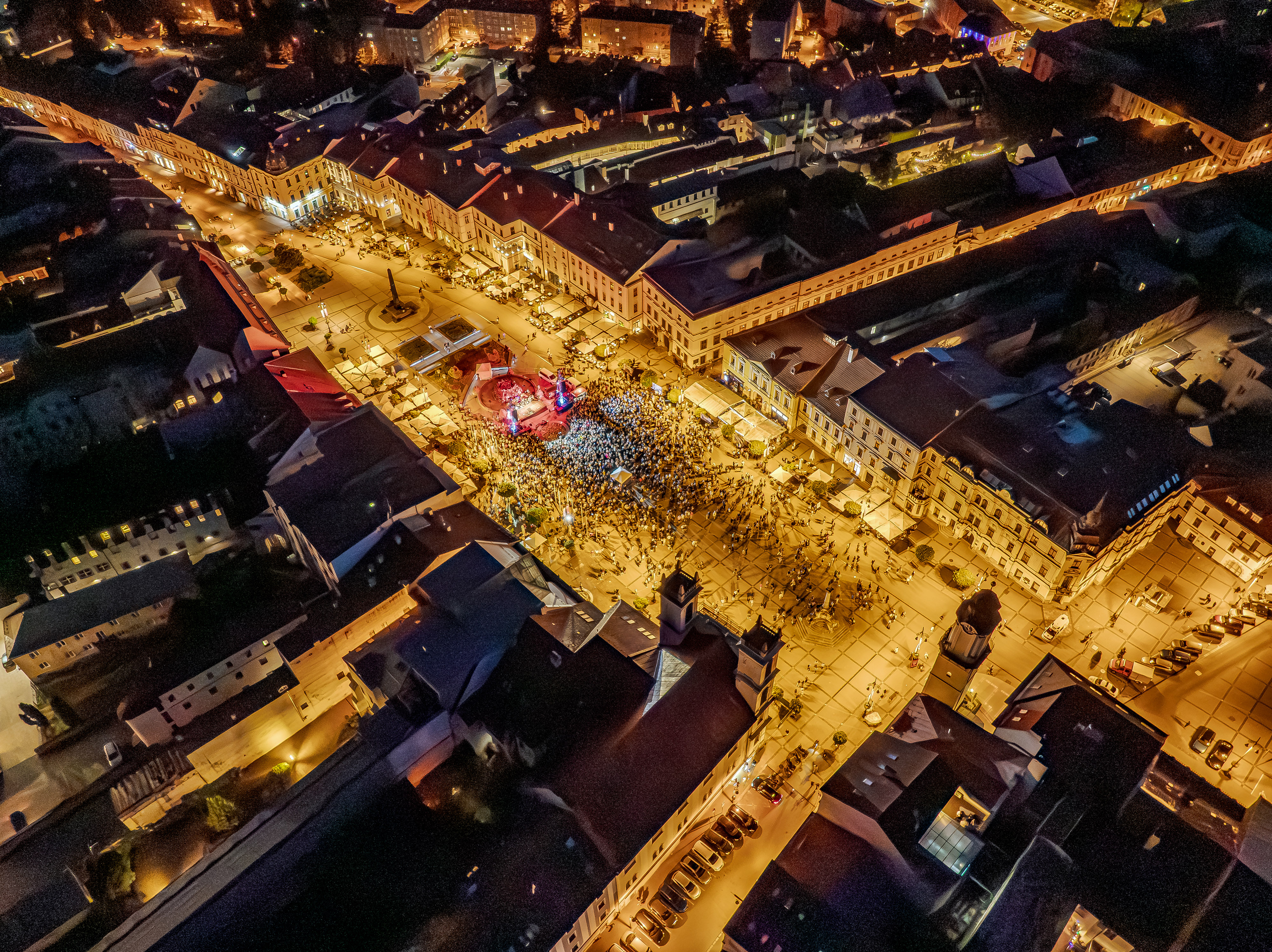 Nočný letecký pohľad na osvetlené historické centrum mesta s podujatím
