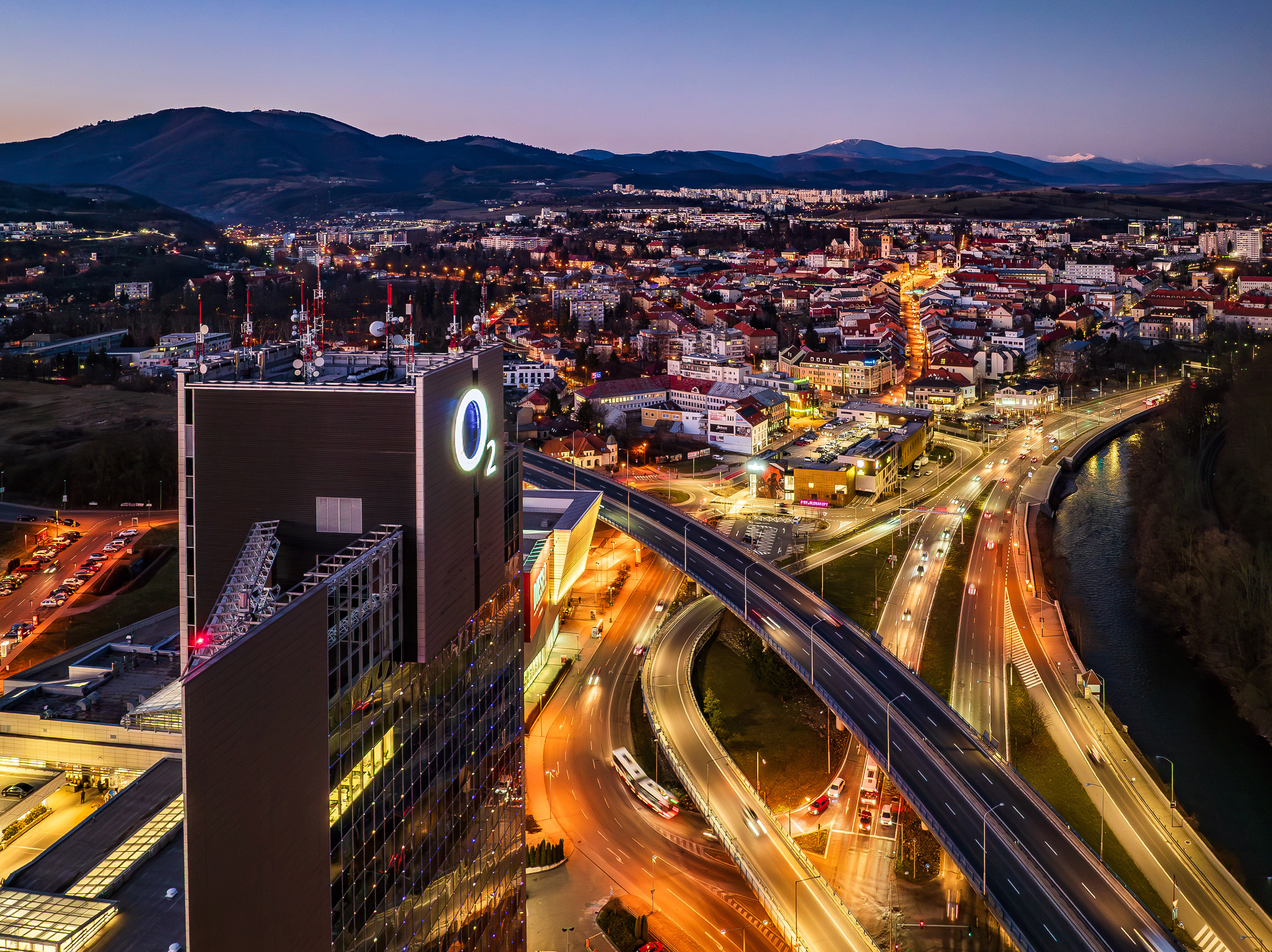Večerný letecký pohľad na Banskú Bystricu s budovou Europa Business Center a osvetlenými cestami